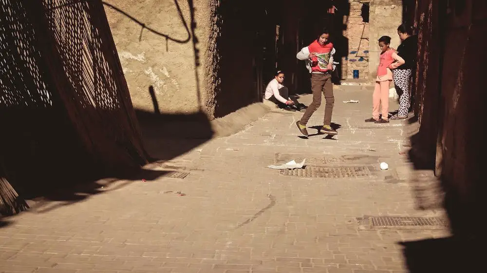 children playing hopscotch in an alleyway