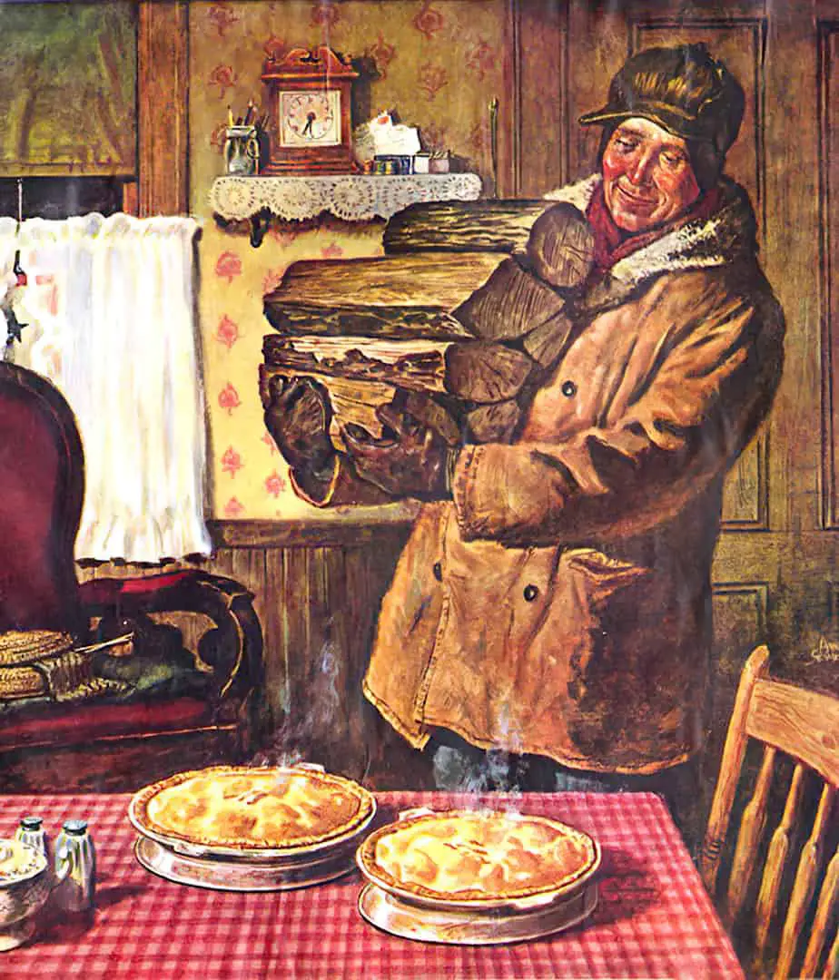 A man carrying logs for the fire admires pies cooling on a table inside a cottage.